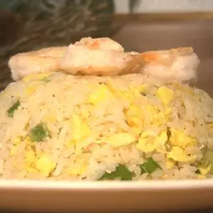 Shrimp and egg fried rice garnished with green onions, served on a white plate.